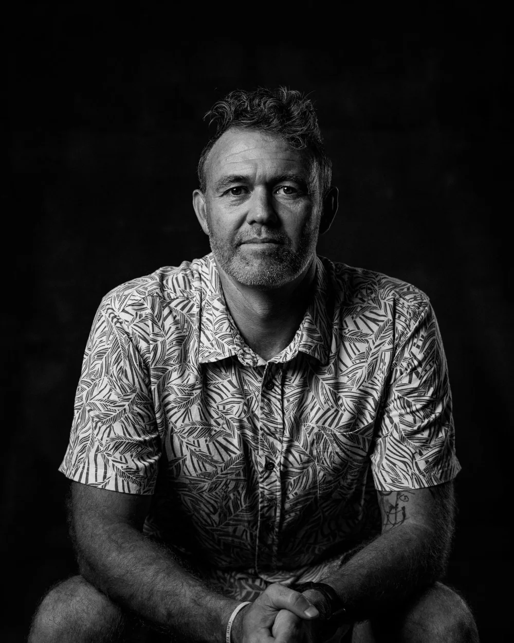 Portrait of Chris Pierce, seated, hands clasped
